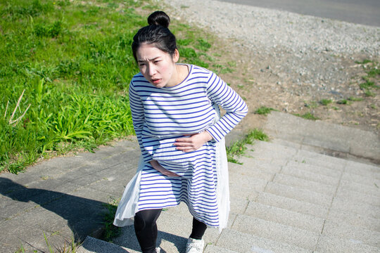 A young pregant Asian woman hard to climb the stairs