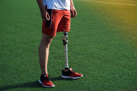 Close up of a man athlete with a prosthesis on his leg standing at the stadium on the field. Sport concept