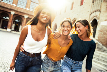 Three young diverse women having fun on city street outdoors - Multicultural female friends...