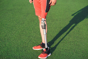 Fototapeta premium Close up of a man athlete with a prosthesis on his leg standing at the stadium on the field. Sport concept