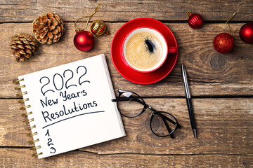 New year 2022 resolutions on desk. 2022 goals with notebook, coffee cup, eyeglasses, Christmas...