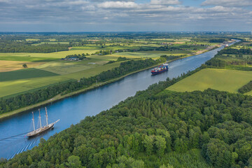 Aerial view of Kiel Canal with container ship and  traditional sailing vessel.Container cargo ship...