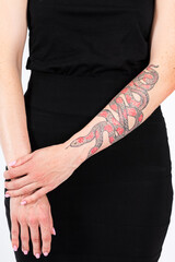 Caucasian Female With Snake Tattoo on Her Hand Posing in Black Dress Over White.