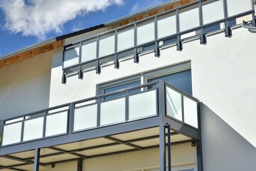 Balkon mit Edelstahl-Geländer und Sichtschutz aus Milchglasplatten an der Fassade eines modernen Mehrfamilien-Wohnhauses