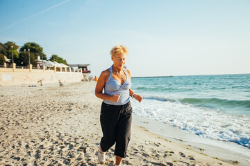 Active senior woman stretching by the sea at sunrise