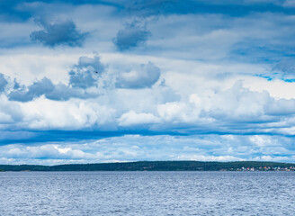 Small private helicopter over the lake, belve clouds in the sky