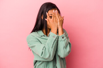 Young latin woman isolated on pink background  blink through fingers frightened and nervous.