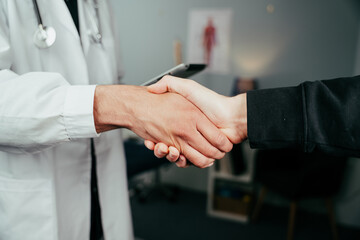 Close up male nurse holding digital tablet shaking hands with caucasian patient