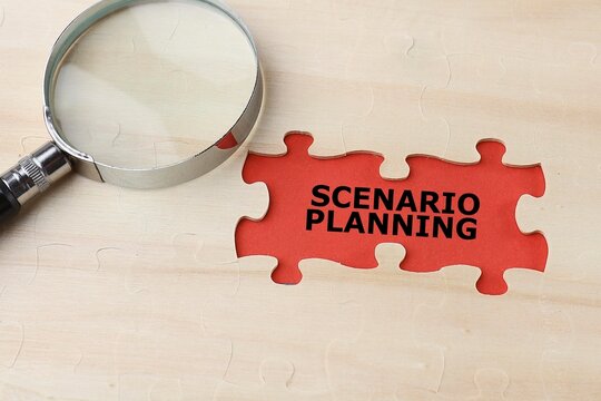 Scenario planning concept. Phrase on SCENARIO PLANNING written on the reb background. A magnifying glass on the missing puzzle. Noise is visible due to the texture on the subjects