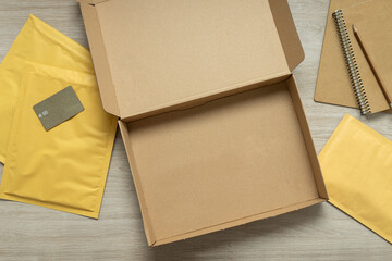 Top view of opened box,padded mailers,credit card,notebooks on the wooden table.Online commerce,payment.Empty space