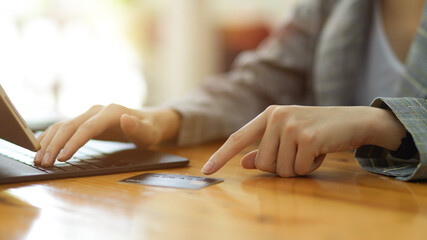 Closeup female entering credit card number by using on digital tablet