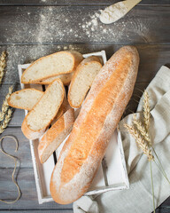 Sliced bread on a wooden background. Baguettes from the bakery. Bread still life. Wheat ears and flour. Baking in a wooden box. Serving loaves.