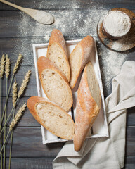 Sliced bread on a wooden background. Baguettes from the bakery. Bread still life. Wheat ears and flour. Baking in a wooden box. Serving loaves.