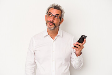 Middle age caucasian business man holding a mobile phone isolated on white background  dreaming of achieving goals and purposes