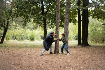 Arabian father playing with son near tree in park