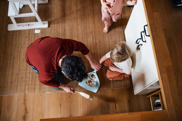 Top view of father with small children sweeping shards at home, daily chores concept.