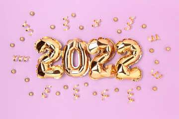 2022 gold inflatable balloons and confetti on a purple background. Holidays concept.