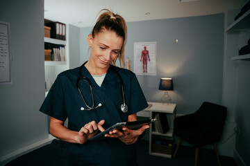 Caucasian female doctor working in clinic typing on digital tablet