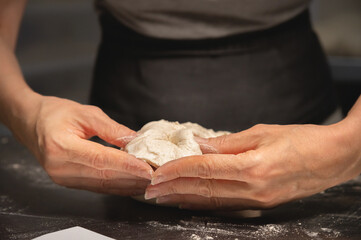 close-up of female hands kneading dough for making artisan bread at home bakery