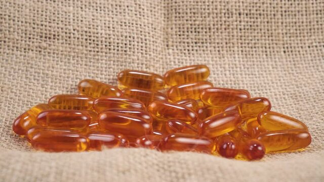 A hand takes a lecithin supplement capsule on a rough rustic burlap napkin close-up. Medical natural pill
