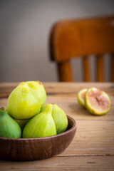 Top view of green figs, on wooden table, with chair in background, selective focus, vertical, with copy space