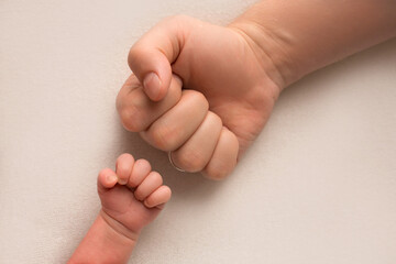 Dad and newborn boy son keep their hands in a fist, small and big fists. Father and son, the first...