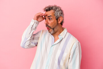 Middle age caucasian man isolated on pink background  looking far away keeping hand on forehead.