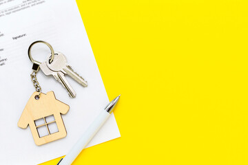 Keys with house shaped keychain and pen on real estate mortgage loan document, contract agreement...