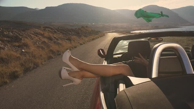 Woman taking off clothes in a cabriolet car. Best friends spend summer time together. The girls are happy and enjoy life. The road by car to the sea. Friendship and love forever. The beauty of Greece.