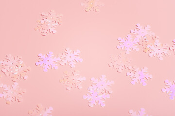 Holographic shiny snowflake sparkles on pink background. Close up. Selective focus.