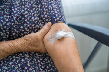 Asian senior or elderly old lady woman patient show cotton wool stop bleeding, after blood drawing testing for annually physical health check up to check cholesterol, blood pressure, and sugar level.