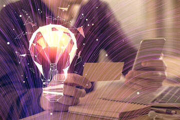 Double exposure of man's hands holding and using a digital device and bulb hologram drawing. Idea concept.