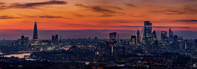 Poster Wide panoramic view of the illuminated skyline of London, United Kingdom, during evening time with orange sky © moofushi