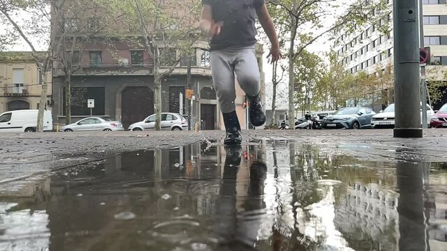 Cute small girl jumping in rain puddle