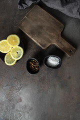 Old cut board on wooden background with vintage napkin, spices and limon for ingredients mocked up.