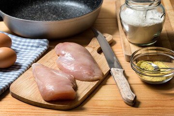 Chicken fillet on a cutting board ready for grilling. Raw chicken breast with grill pan, flour and spices. Chicken steaks for cooking