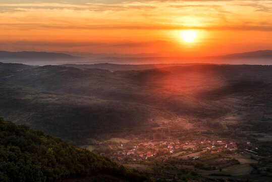 Sunset over small village between hills and mountains. Shades of Mountain layers in sunset © Ivan