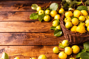 there are a lot of pears on the wooden table. In the middle is a cutting board on which pears are cut into two halves and a knife