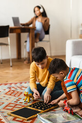 African american woman working while her kids playing at home