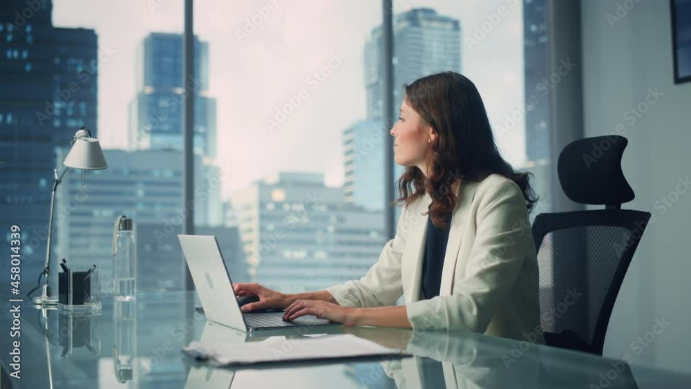 Wall mural portrait of young successful caucasian businesswoman sitting at desk working on laptop computer in c