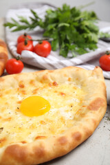 Fresh delicious Adjarian khachapuri on light table, closeup