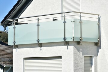 Fototapeta premium Moderner Balkon mit Sichtschutz aus Mattglasplatten und Metall-Geländer an einer Neubau-Hausfront