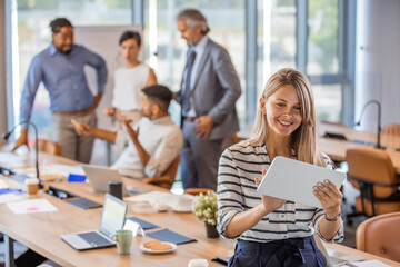 Waist up portrait modern business woman in the office with copy space. Portrait of a young business woman in the modern office, and a team behind her. Beautiful young business woman