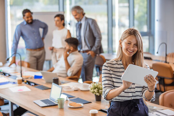 Obraz premium Beautiful business woman holding tablet computer in office. Portrait of happy businesswoman using digital tablet in agency. Successful business woman in casual clothing working on tablet.