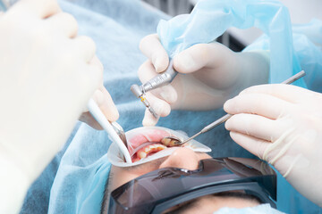 Dentist's hands in sterile gloves close-up, with an implantation tool.