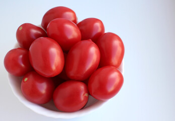 Red conical tomatoes in a cup on a white background, top view