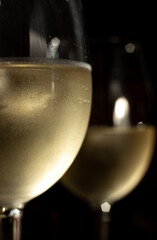 macro photo of two glasses of white wine. Two glasses with chilled wine in it and condensation and drops on them