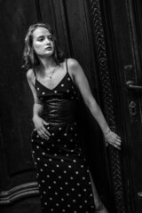 Black and white stylish portraits of a brunette young girl in an urban environment. Black summer dress with white polka dots, red lips and a slight melancholy