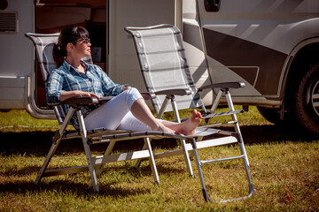 Woman resting near motorhomes in nature. Family vacation travel, holiday trip in motorhome RV,...