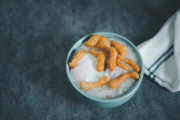 Thai porridge rice gruel in bowl congee with soft-boiled egg and deep-fried dough stick topping